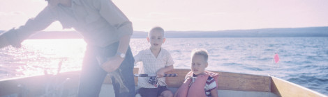 A dad in a fishing boat with two little boys