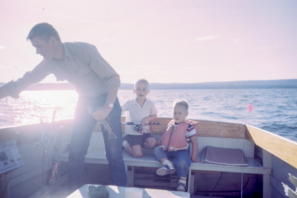 A dad in a fishing boat with two little boys